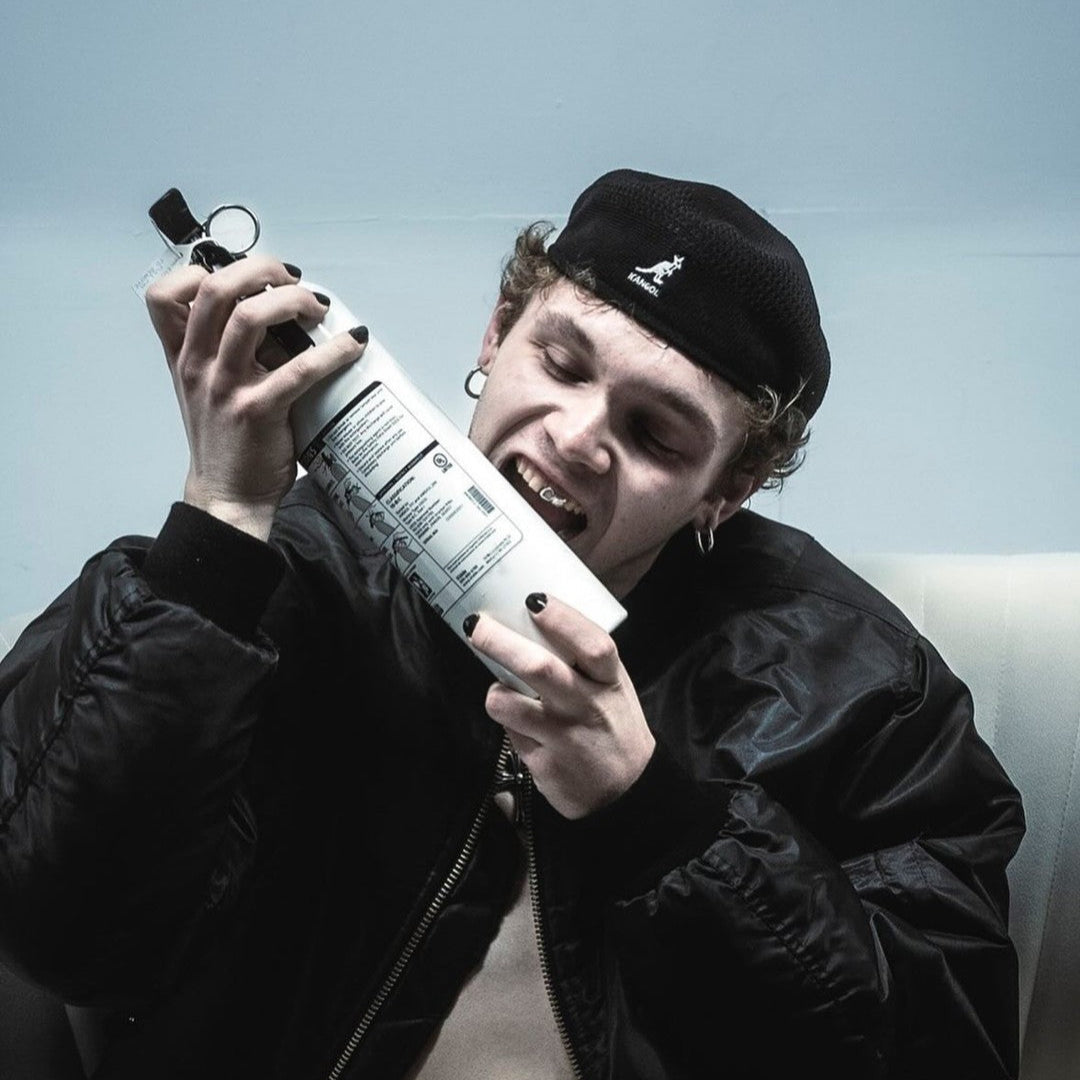 Person holding a large white object with a black cap against a light blue background